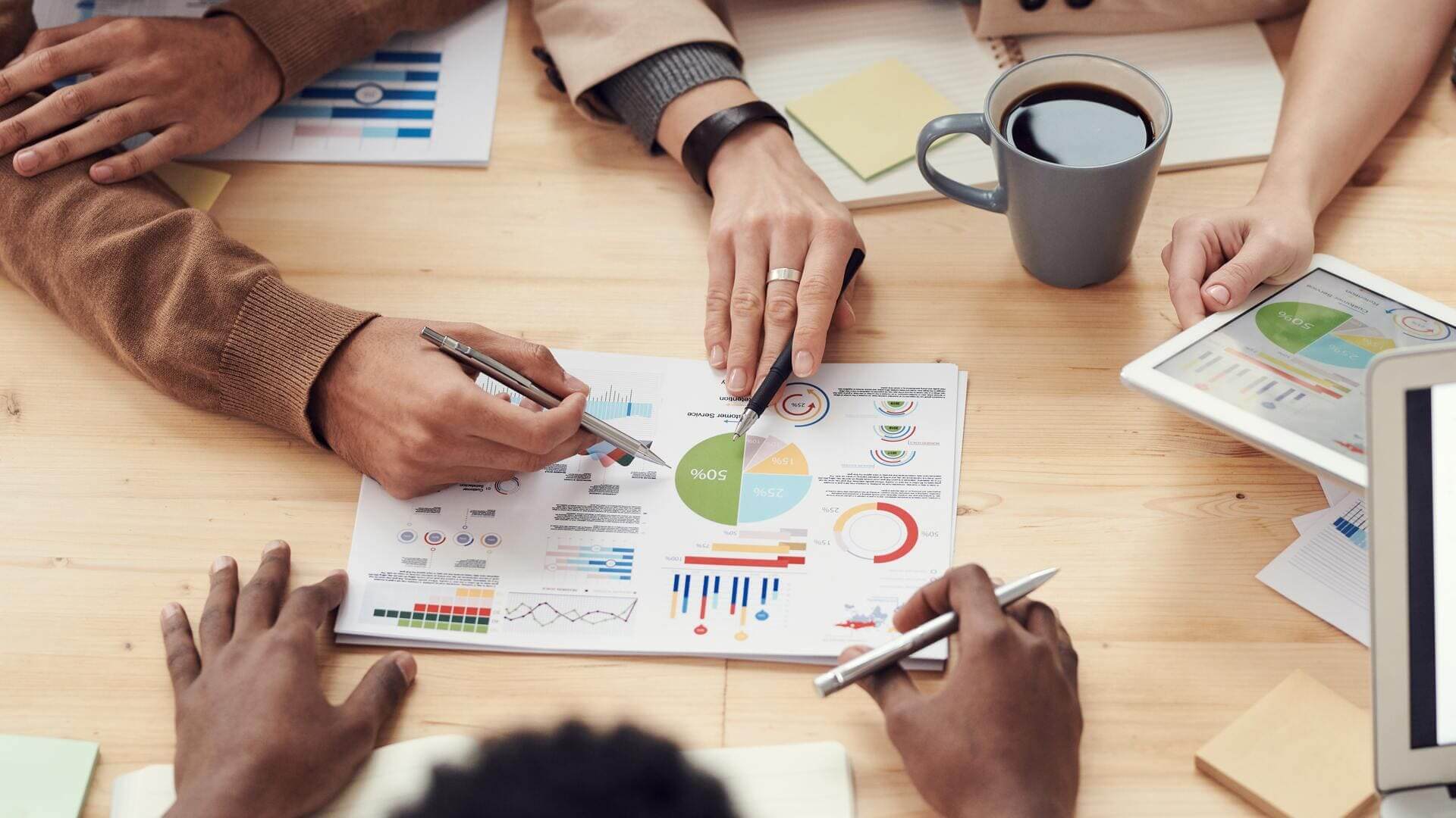 Pessoas analisando gráficos sobre uma mesa